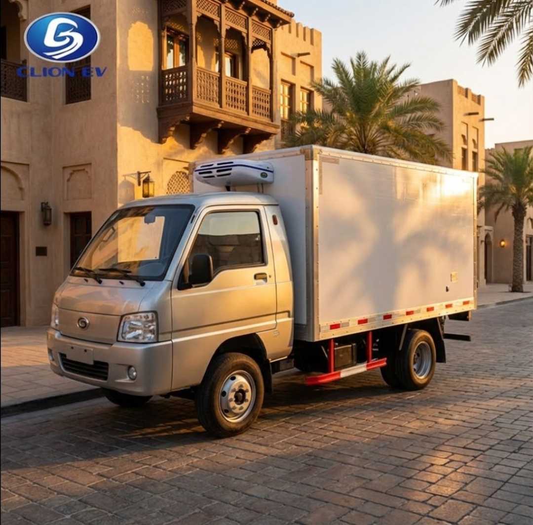 Small refrigerated truck parked on a street with palm trees and buildings in the background.