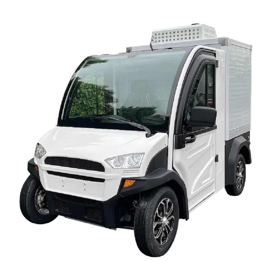 UAE golf cartz three-quarter front studio shot of a white electric refrigerated delivery vehicle with an enclosed cab and an insulated rear cargo box, set against a white background. This compact electric NEV or refrigerator work cart features a black roof, black trim, and a white refrigeration unit visible on top of the cargo box. The vehicle is equipped with custom black and silver wheels, highlighting its function for cold chain last-mile delivery.
