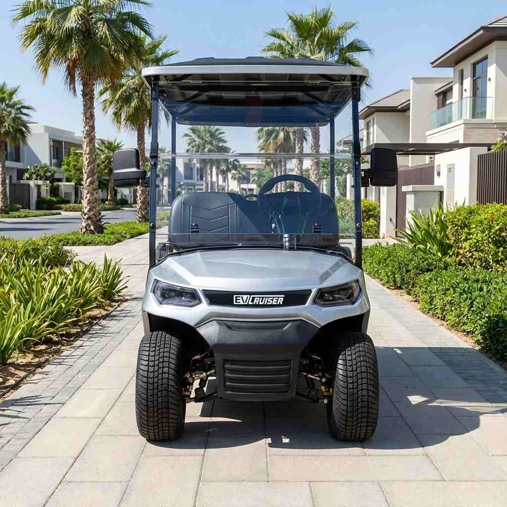 Silver golf cart with a clear canopy on a paved path with palm trees and houses in the background.