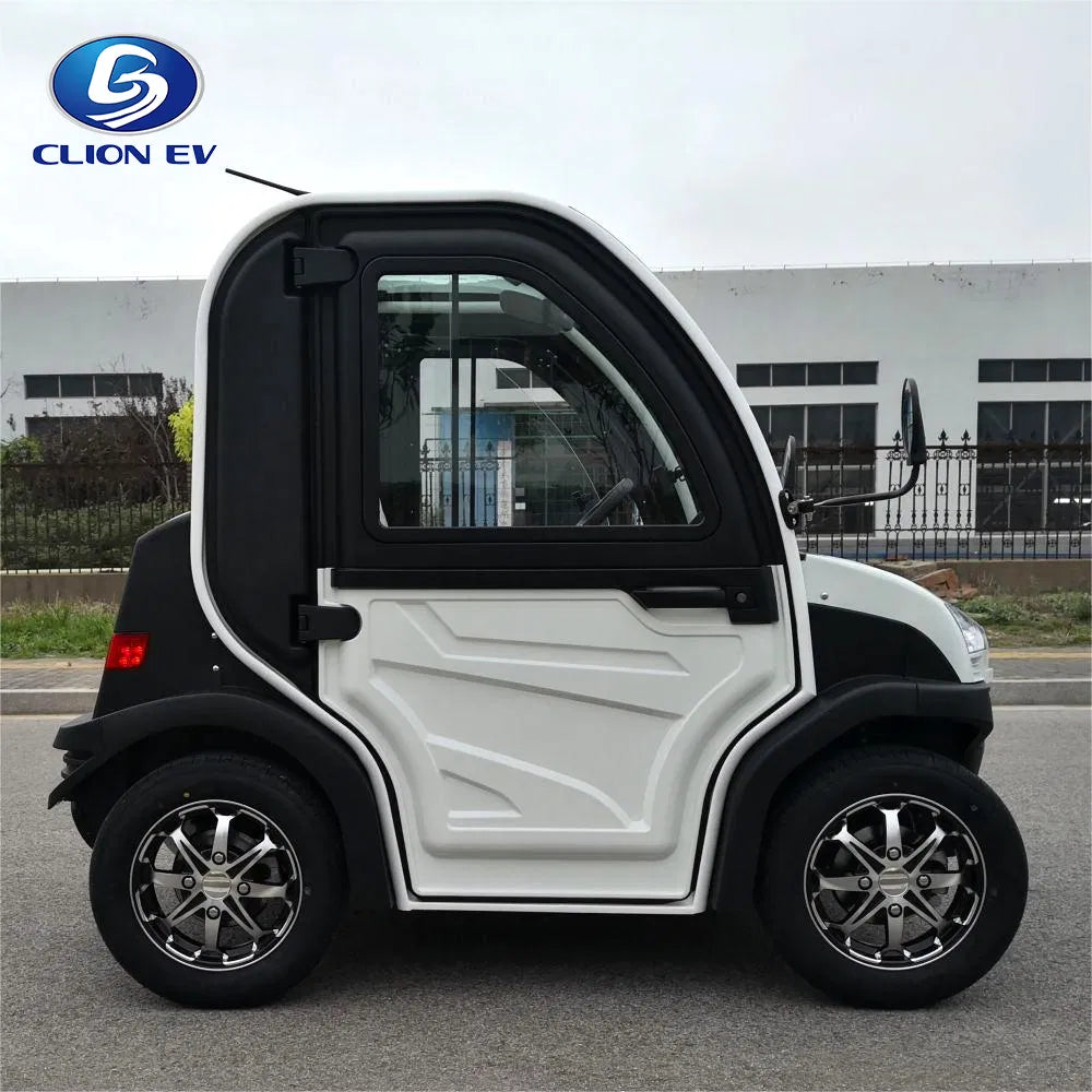 UAE golf cartz side profile view of a white and black two-seater electric vehicle with a fully enclosed cab, parked on an asphalt road. This compact low-speed electric car or NEV features a large driver's door with a pronounced white panel design, black fender flares, and a small rear window. It is equipped with custom black and chrome alloy wheels, emphasizing its all-weather neighborhood electric car design.