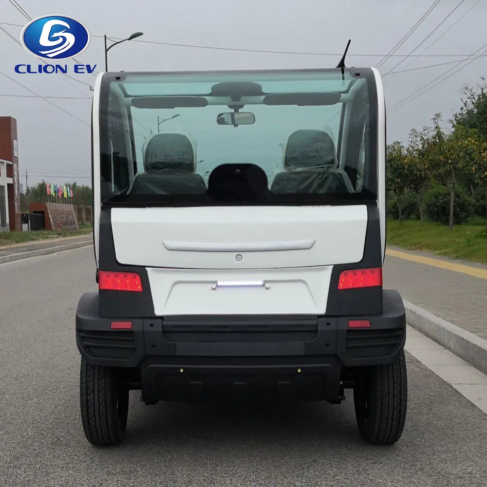UAE golf cartz rear view of a white and black two-seater electric vehicle with a fully enclosed cab, parked on an asphalt street. This compact NEV or low-speed electric car features a large rear windshield, wraparound rear brake lights, a black bumper, and a horizontal white LED reverse light bar. The image highlights the modern, compact design of the neighborhood electric car.