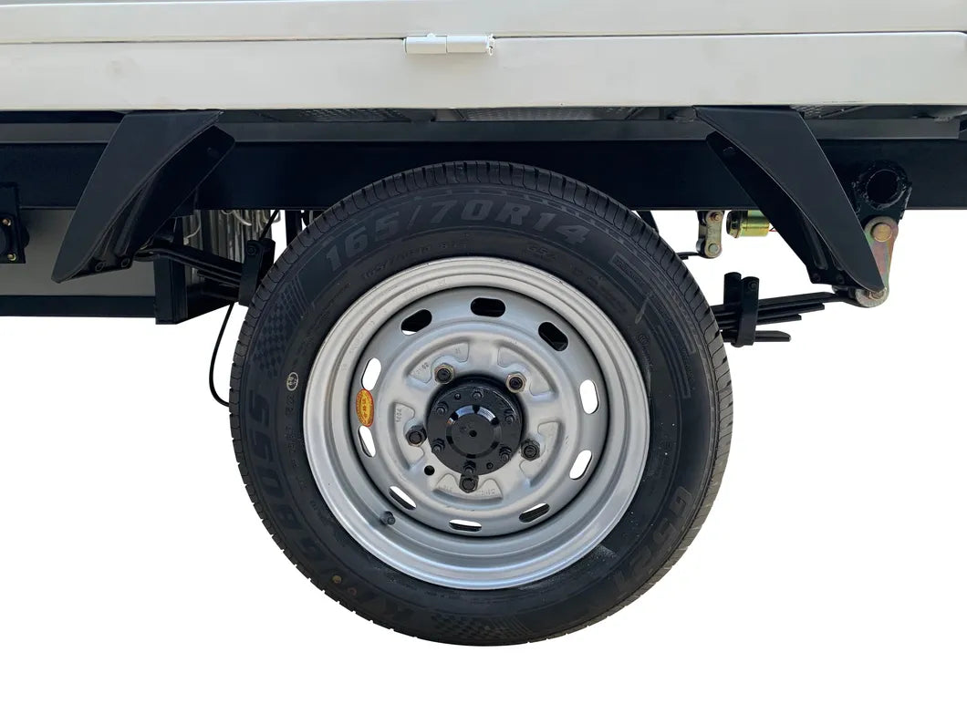 UAE golf cartz close-up detail of the rear wheel and tire on a white electric flatbed truck. The image highlights a silver steel rim with a black hub cap and a tire labeled "165/70R14", positioned beneath the white cargo bed. This detail shot emphasizes the robust utility tire and wheel assembly of the electric commercial vehicle or work truck.