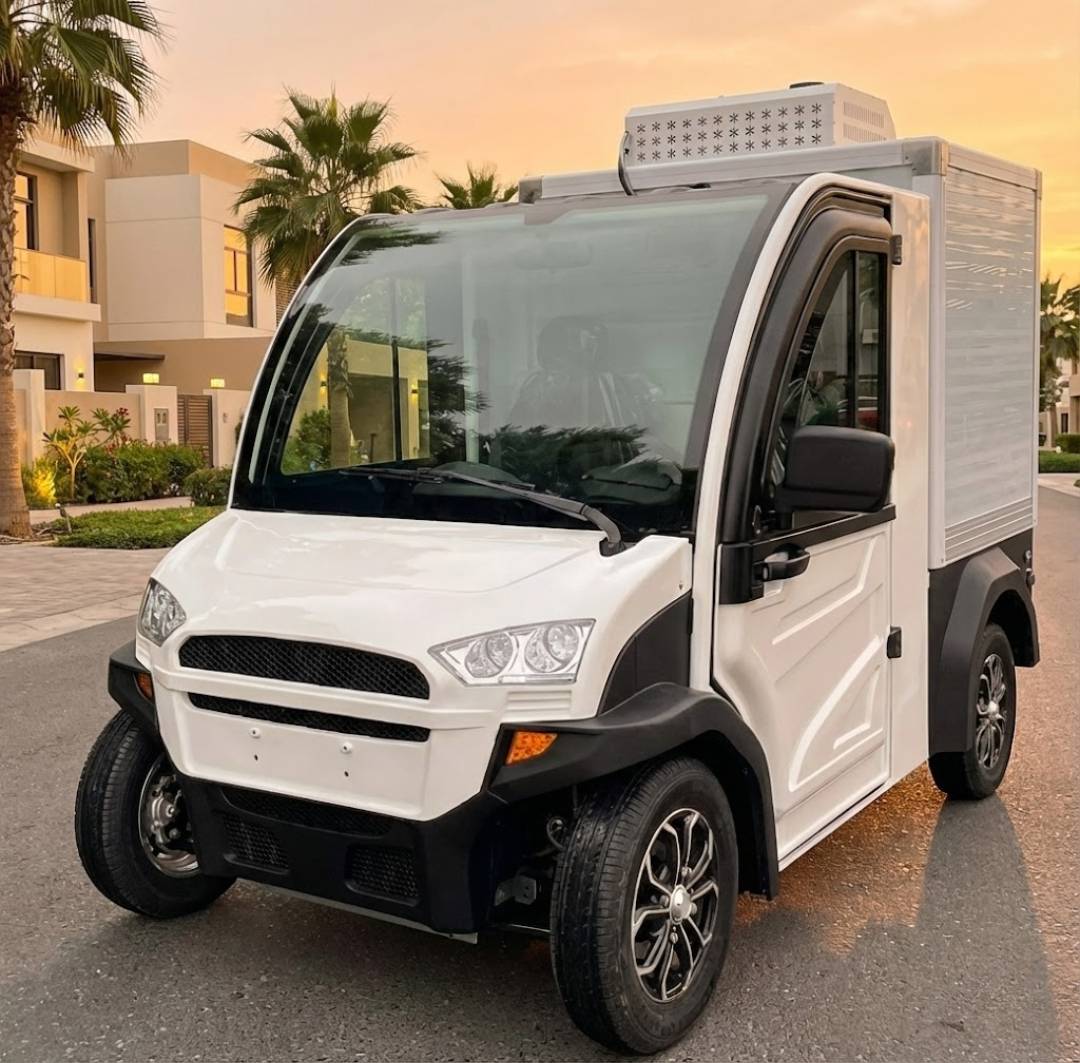 White delivery vehicle with black accents on a street with palm trees and buildings in the background.