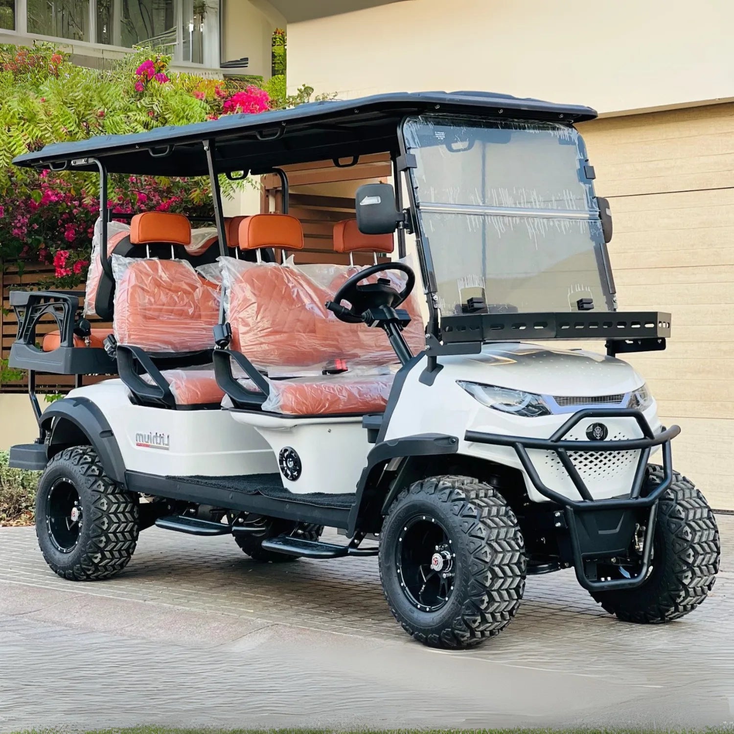 White golf cart with orange seats parked on a wooden deck.