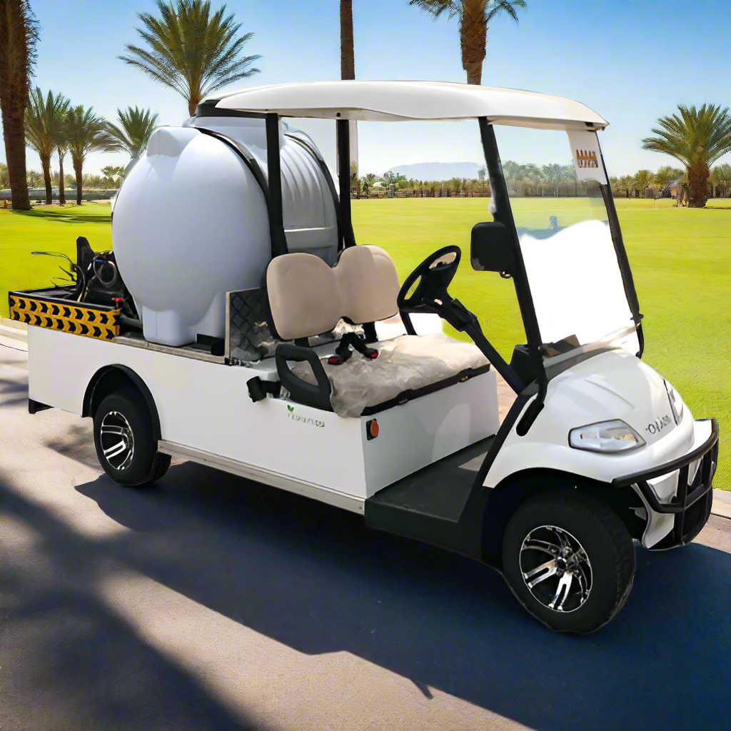 UAE golf cartz three-quarter front view of a white utility electric vehicle designed as a sprayer or water transport golf cart, parked on an asphalt path in a sunny resort or golf course. This specialized two-seater work cart features a large white spherical water tank and a black and yellow striped rear utility platform holding a pump and hose. The cart has tan seats, a white roof, and custom black and silver wheels, highlighting its function as a maintenance vehicle for irrigation or pest control.